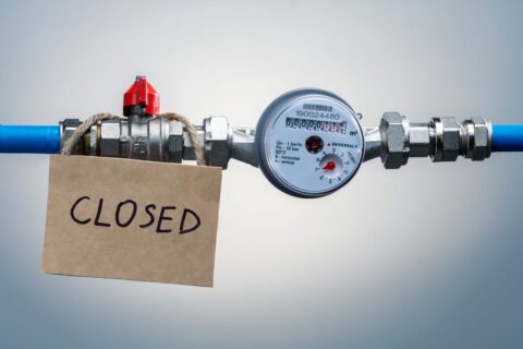 Water meter with shutoff valve and closed sign attached to pipe