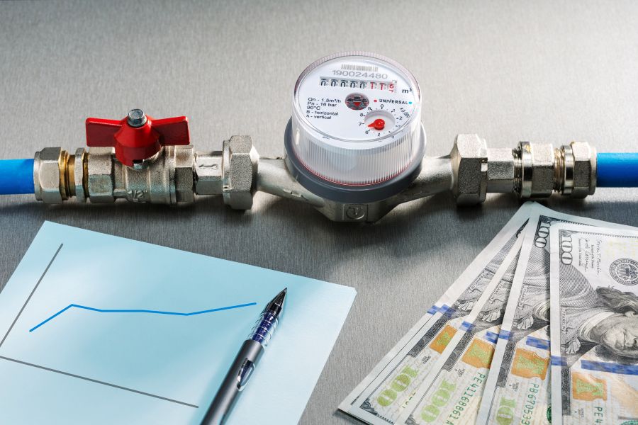 Water meter valve connected to pipe with cash bills and chart on table
